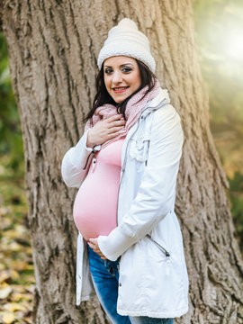 Portrait of smiling pregnant young woman, light effect