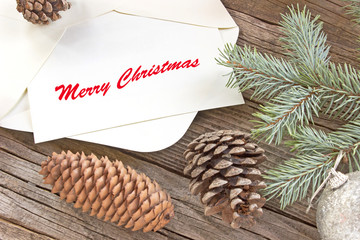 Merry Christmas with pine tree needles,baubles and cones on wooden background