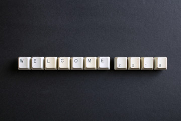 Welcome 2018 New Year. Flat lay view from above on the table with computer keyboard keys buttons on a dark background.