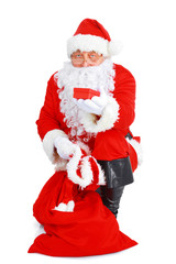 Real Santa Claus carrying big bag full of gifts, isolated on white background