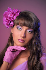 Naklejka premium Beautiful brunette with purple make-up, flower in hair and glove on hand