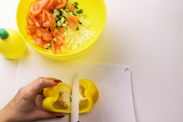 Girl preparing salad from fresh vegetables with lemon juice.