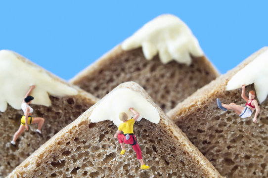 A group of toy mountaineers on mountains, made of healthy rye bread and creamy cheese. Ecotourism and healthy eating concept.