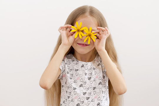 Summer mood. Happy gerl holding flowers in front of her eyes .