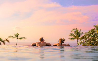 Romantic couple looking at beautiful sunset in luxury infinity pool - Powered by Adobe