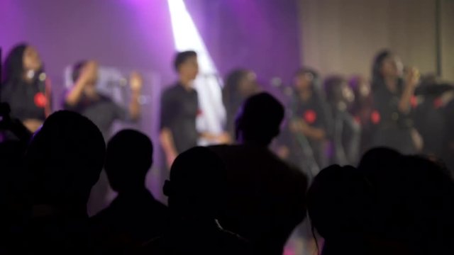 Black Africans pray in the concert hall. Dance and raise hands up. Shooting through your hands in the backlight.