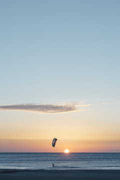 Man kitesurfing on windy day at sunset