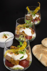 portion of gyros in a glass with lettuce, tomato and  meat covered with tzatziki