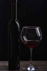 Bottle of wine near glass on black background