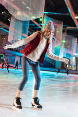 excited beautiful young woman ice skating on rink