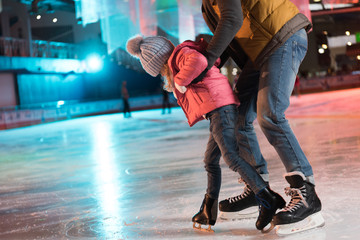 cropped shot of father and daughter hugging and having fun on skating rink