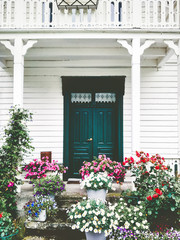 White wooden country house entrance door terrace cozy exterior with flowers design decoration and balcony retro style traditional building