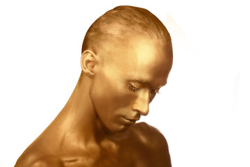 The guy painted in gold paint. completely. portrait. beauty on a white background. Shiny Gold foil. looked down modestly