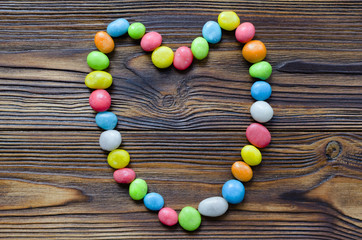 heart from multicolored candy on wooden background