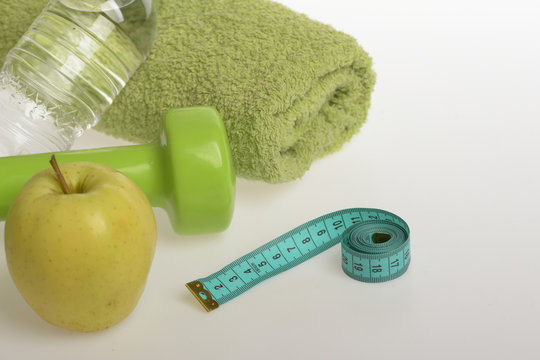 Dumbbell in green color, water bottle, measure tape, towel, fruit