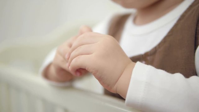 Close-up of the hand of a little girl standing in a baby bed