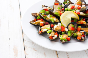 Steamed mussels with peppers and onion on white  wooden table