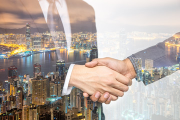 Double Exposure of a businessman handshake on the Hong Kong skyscraper background.
