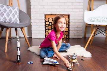 Young child girl female playing with cosmos's toys constructor: rocket, shuttle, rover, satellite...