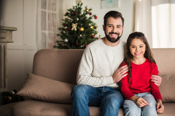 Obraz premium father hugging daughter while sitting on sofa at home