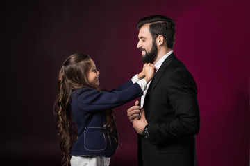 daughter fixing father tie and looking at each other on burgundy