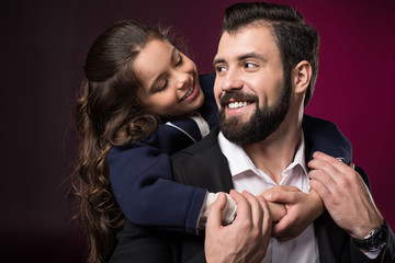 daughter hugging father from back and they looking at each other on burgundy