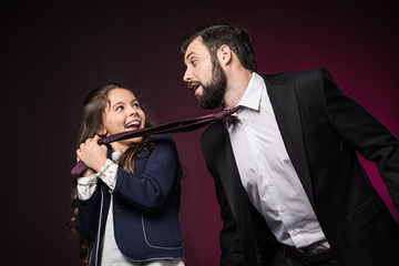 happy daughter pulling father tie on burgundy
