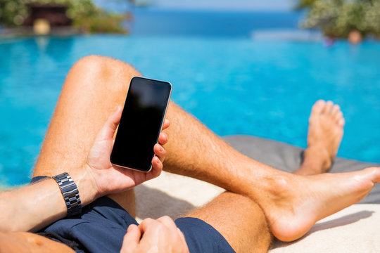 Man with mobile phone by the pool