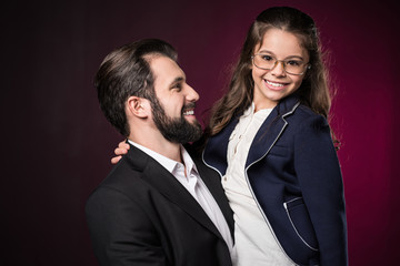 smiling father holding daughter on burgundy
