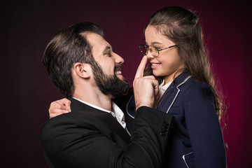 father touching daughter nose with finger on burgundy