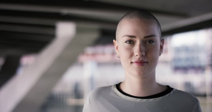 Close portrait of beautiful young woman with buzz cut smiling into camera