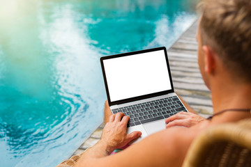 Man with laptop computer by the pool