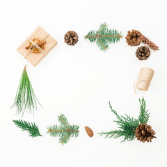 Christmas frame made of gift, branches of winter tree and pine cones on white background. Flat lay. Top view