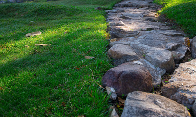 The large rocky walkways in the park are lush green with lawns.