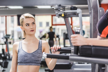 Fototapeta na wymiar young woman looking at other woman exercising on gym machine