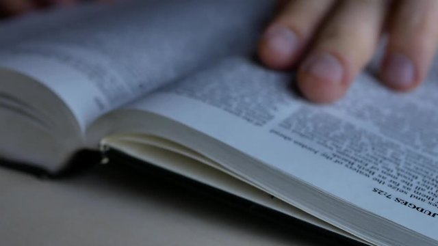 Man reading and studying Holy Bible lying on table