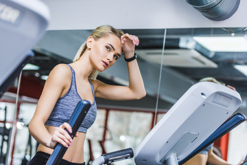 exhausted sportive woman working out on elliptical machine at gym