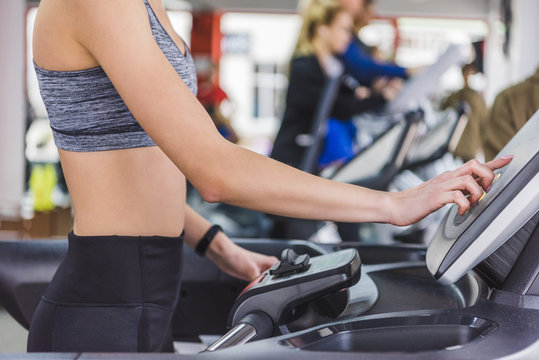 cropped shot of woman running on treadmill at gym