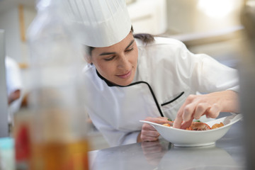 Fototapeta na wymiar Closeup of cook chef in professional kitchen preparing dish