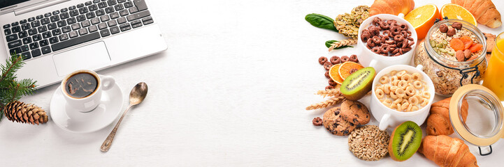 Business breakfast, muesli, coffee, milk, fruits, nuts and seeds, on a wooden surface. Top view. Free space for text.