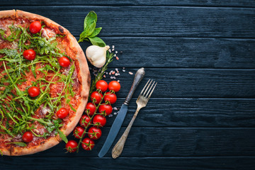 Pizza Primavera. Cherry tomatoes, arugula, cheese. On a wooden background. Top view.