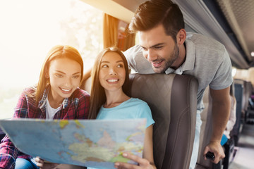 Tourists look at the map and choose where to go next. They discuss the upcoming journey and smile.