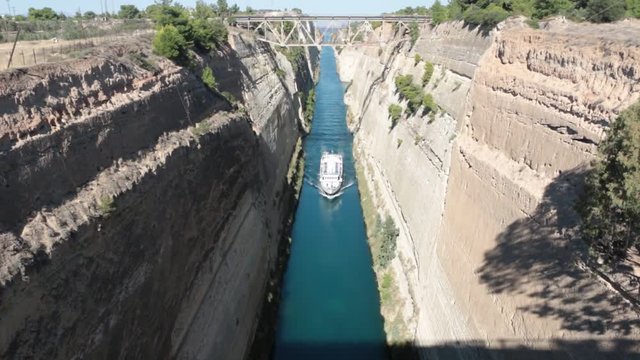 ferry boat swimming through beautiful and stunning sky blue isthmus canal in Corinth in Greece