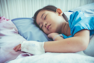 Illness asian child admitted in hospital with saline intravenous on hand.