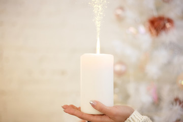 in the hands of a burning candle magic Christmas tree