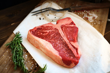 raw porterhouse steak with herbs on a wooden Board