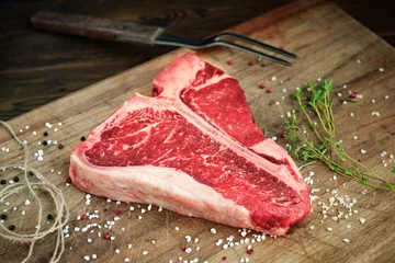 Tuinposter raw t bone steak on wooden Board rustic style © Andrey