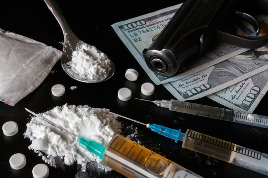 Drug heroin, syringes, money, guns on a dark background copy space, concept of crime and addiction