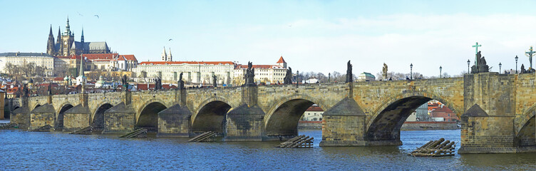 Obraz premium A panoramic view of the Prague Castle, Vltava river and the Charles Bridge. Unidentified tourists admiring the famous city