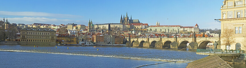 Obraz premium A panoramic view of the Prague Castle, Vltava river and the Charles Bridge. Unidentified tourists admiring the famous city